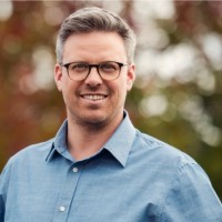 Headshot photo of Mark Richardson, 2026 TLP Participant. Mark has short greying hair worn brushed away from his forehead, dark blue (?) eyes and a slight 5 o'clock shadowy stubble. He is wearing a blue business shirt with the top button undone