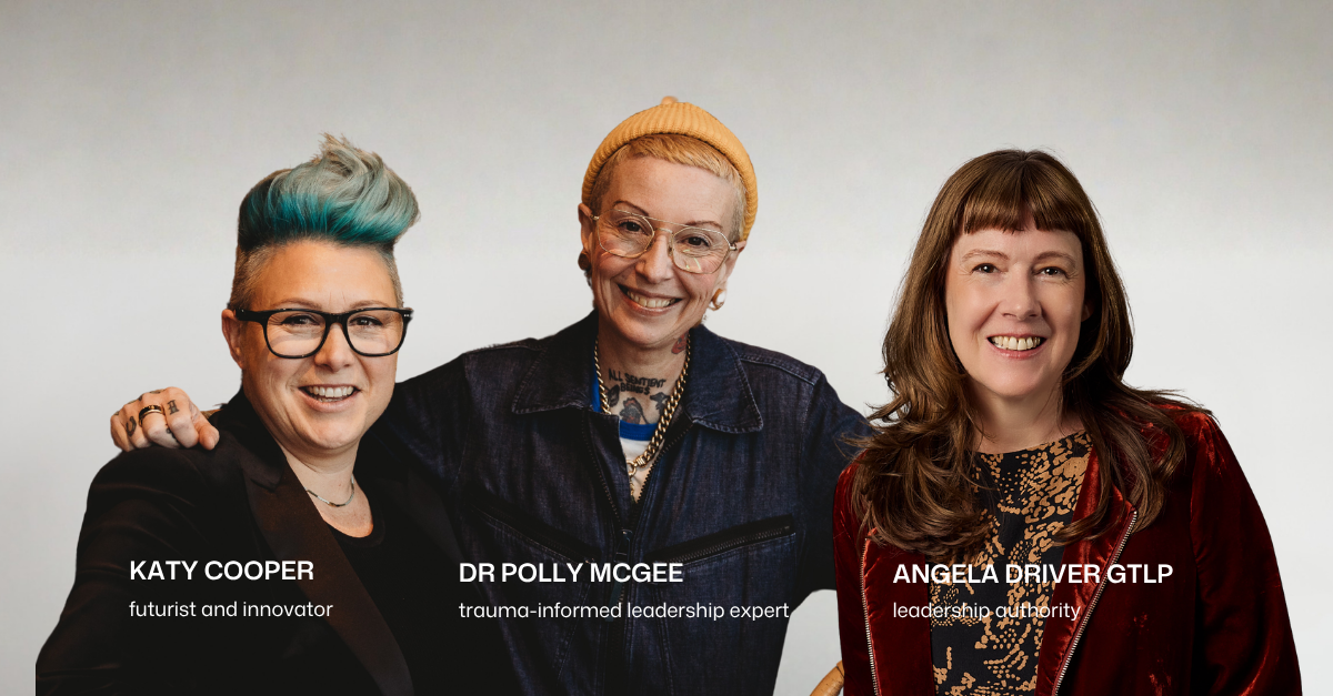 Three women are grouped together facing the viewer. L-R: Katy has short punk green hair and is wearing a black jacket and black framed glasses, Polly is wearing a denim jumpsuit and an orange beanie covers their short hair, with thin gold framed aviator glasses, Angela is wearing a rust velvet jacket and patterned shirt, her hair is long and reddish brown