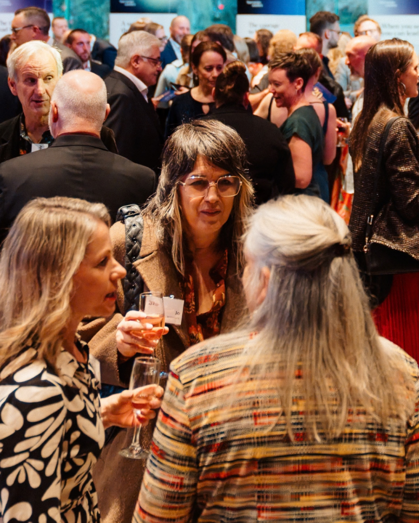 Attendees chatting in small groups at a Tasmanian Leaders networking event, with three women in conversation in the foreground.